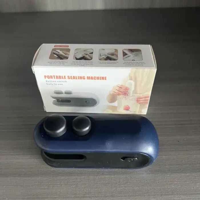 Portable mini bag sealer with magnetic storage navy blue color shown with product packaging box, button switch.