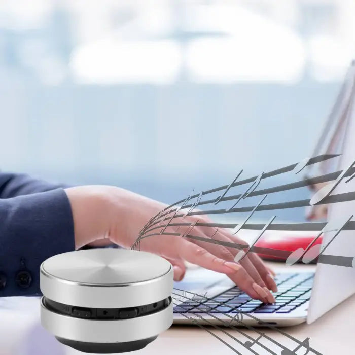 portable music speaker shown with floating music notes while person types on laptop in modern office setting