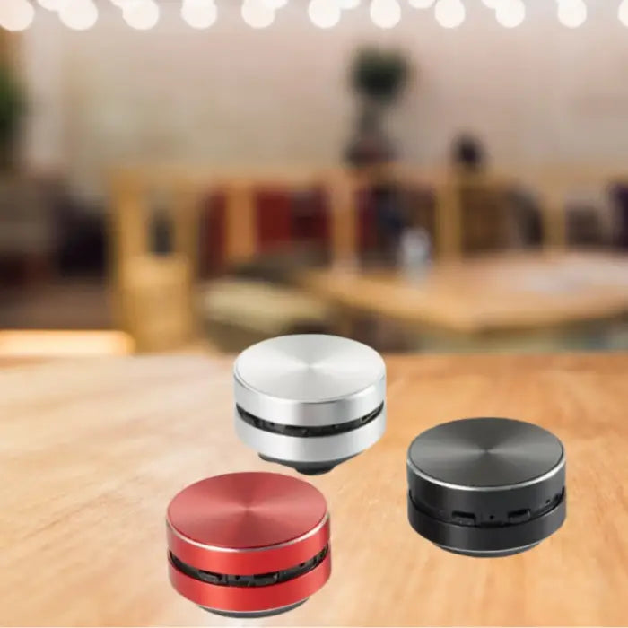 premium portable speakers collection featuring red, silver, and black metallic finishes on wooden surface with bokeh background