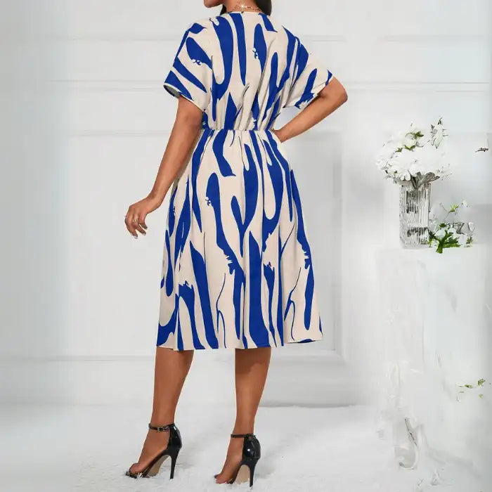  Printed v-neck short sleeve dress in beige and blue featuring a flowy silhouette and elastic waist back.