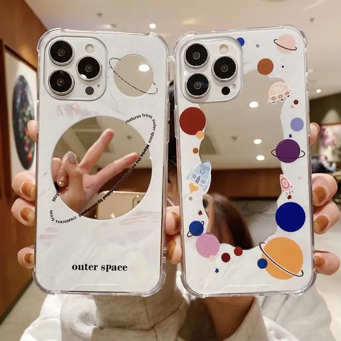 Protective iPhone 15 case featuring colorful space-themed designs with planets, rockets and cosmic elements on clear background