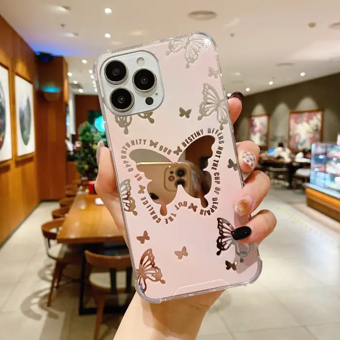 Protective iPhone 15 case with pink background featuring gold butterfly motifs and inspirational text arranged in circular pattern