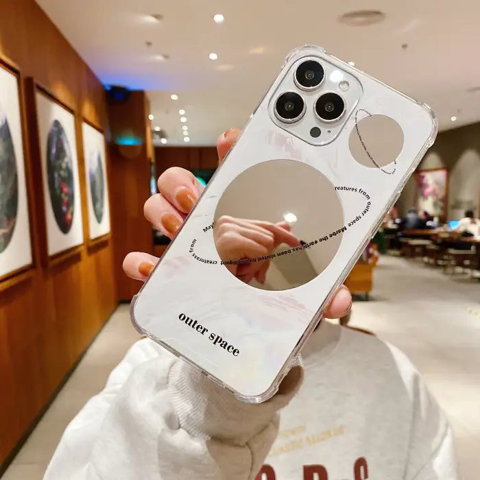 Protective iPhone 15 case showing two space-themed designs with circular mirror elements and minimalist aesthetic for style options