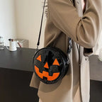 Pumpkin Head Purse in glossy black with bold orange jack-o-lantern face worn crossbody.