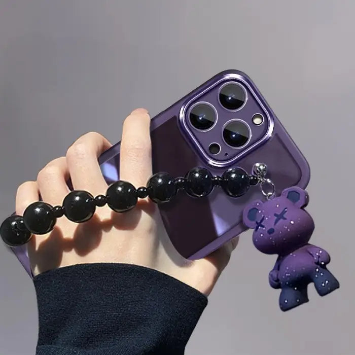 Close-up of Purple Kuwaii Phone Case showing purple bear charm and shiny black bead strap.