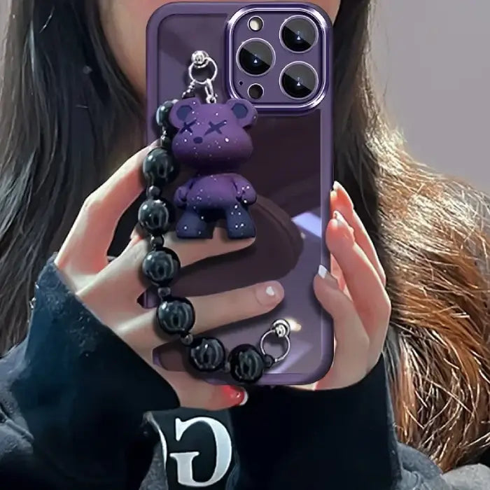 Purple Kuwaii Phone Case with dangling purple bear charm and black beaded bracelet strap.