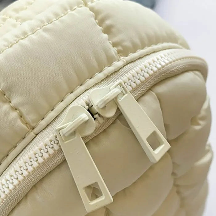 Close-up of cream quilted bag zipper detail showing double zipper pulls