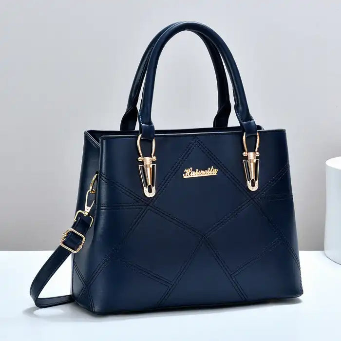  Quilted faux leather satchel handbag in navy blue with diamond pattern, dual handles, gold hardware, front view.