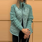 Quilted jacket in sage green with soft quilted panels and textured knit sleeves, delivering lightweight insulation and modern style