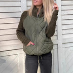 Quilted jacket with olive quilted body and chunky knit sleeves, zip front and pockets, offering cozy warmth and everyday comfort