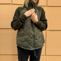 Quilted jacket featuring olive diamond quilting with cable knit sleeves, high collar and zipper, designed for stylish warmth outdoors