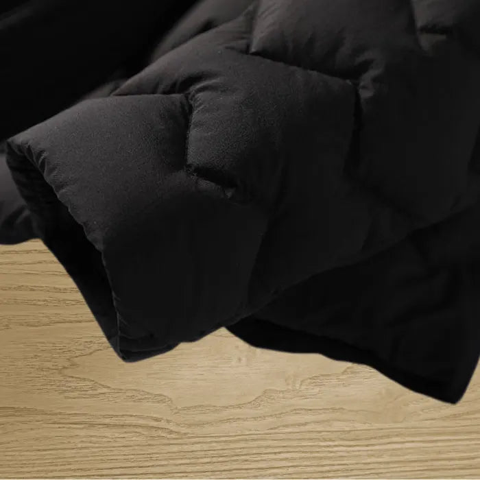 Quilted puffer jacket black sleeve close-up showing thick warm padding and premium winter coat texture for detailed product viewing