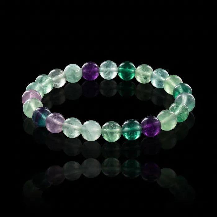Rainbow Fluorite Crystal Bracelet on black reflective surface with vivid green and purple beads, luxury style boosting confidence appeal