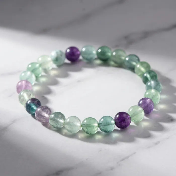 Rainbow Fluorite Crystal Bracelet on marble surface with soft light, showcasing natural green purple tones for peaceful stylish wear