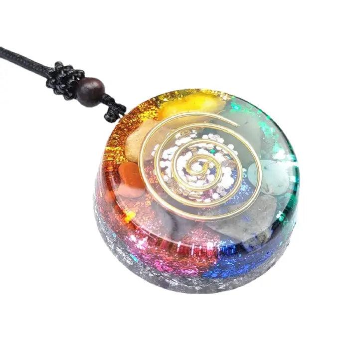 Vibrant rainbow healing pendant with gold spiral design and sparkling gemstones on white background.