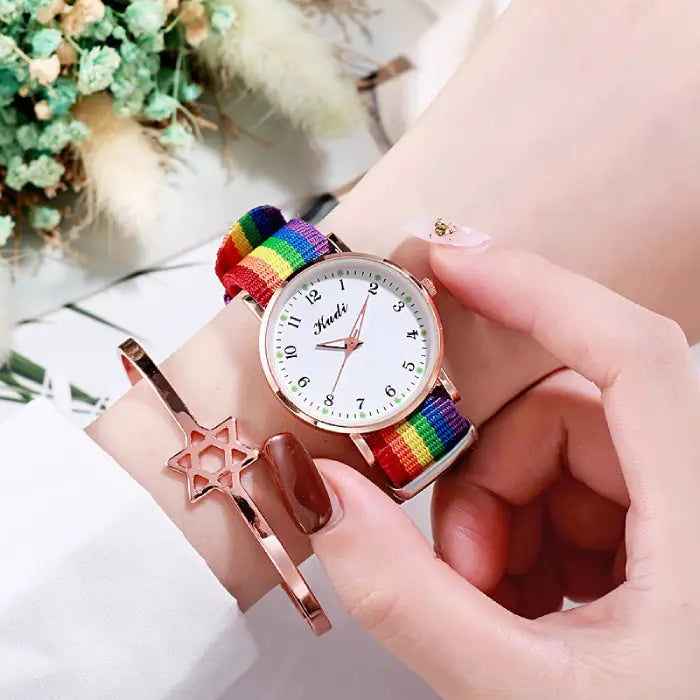 Women's watch with a white dial and rainbow strap, styled with a rose gold star bracelet.