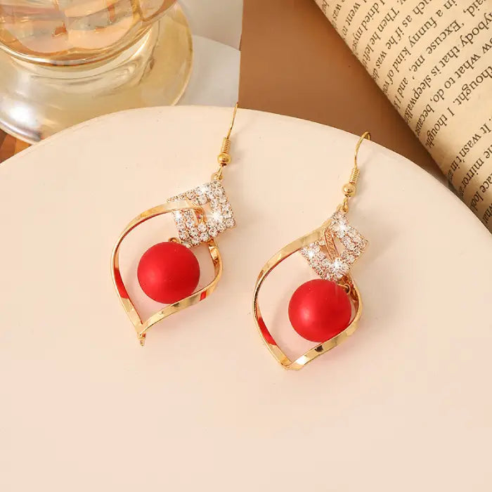 Red bead earrings with gold twist design and crystal accents for trendy fashion jewelry looks.