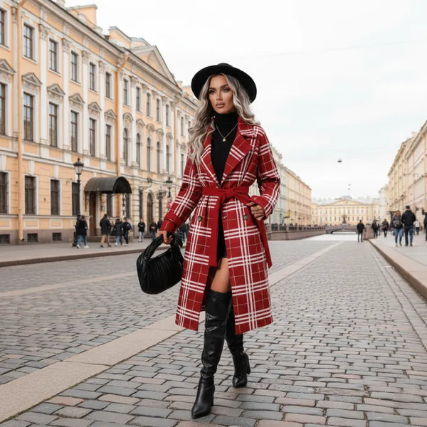 Red belted trench worn while walking a European street, highlighting a plaid coat styled with boots for chic winter fashion.