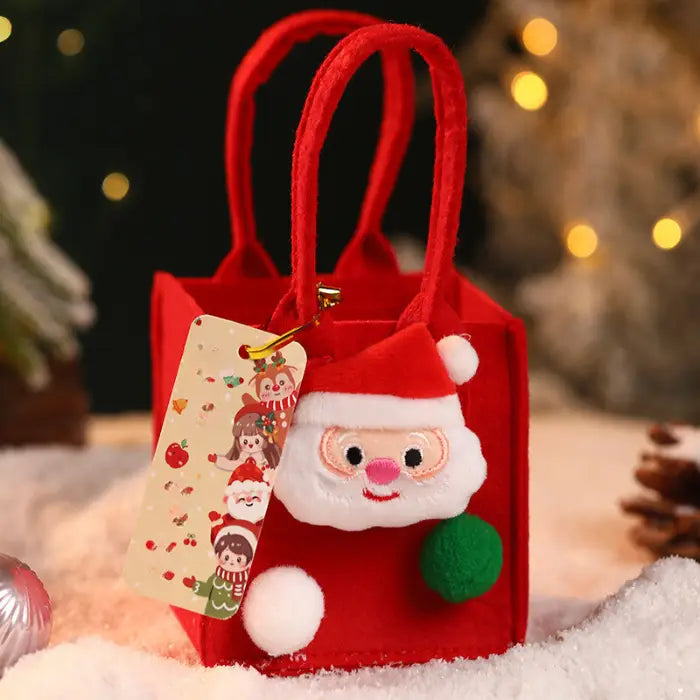 Red Christmas gift bag with a Santa ornament, pom-poms, and a festive holiday tag.