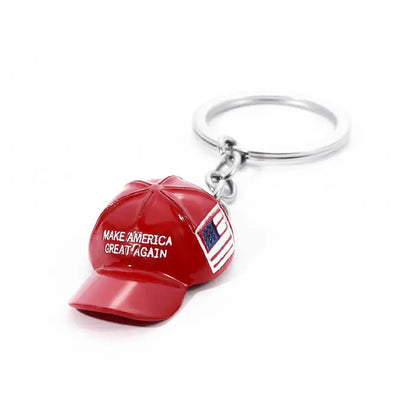 Red hat-shaped keychain featuring "Make America Great Again" text and USA flag on a clean white surface.