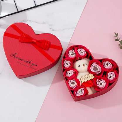 Open red heart-shaped gift box with teddy bear and red and white artificial roses for special occasions.