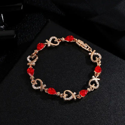 Romantic red gemstone bracelet with heart designs displayed on a luxurious black background.