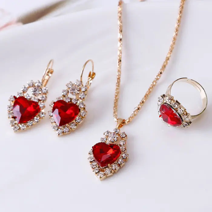 Stunning red gemstone heart jewelry set featuring necklace, earrings, and ring with crystal accents.