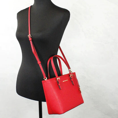 Stylish red Michael Kors leather tote bag with adjustable crossbody strap displayed on black mannequin against white background