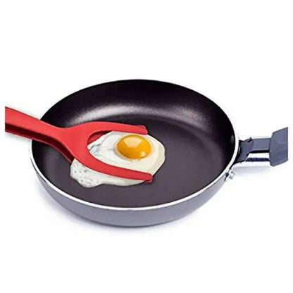 Red silicone spatula flipping a fried egg in a non-stick frying pan for easy meal preparation.