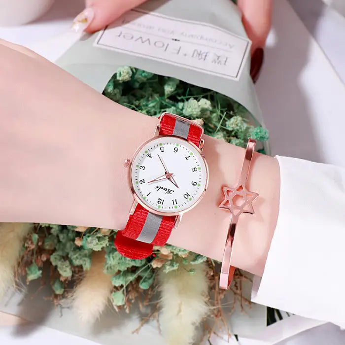 Women's watch with a white dial and red strap, paired with a rose gold star bracelet.