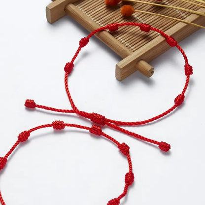 Red string seven-knot bracelets symbolizing protection and good fortune in a minimalist design.