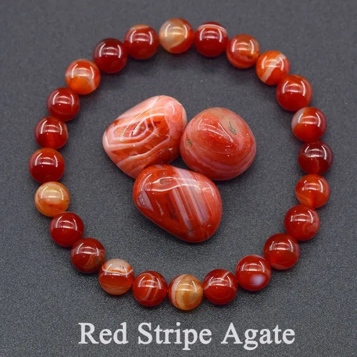 Red stripe agate bracelet and stones on a dark gray background