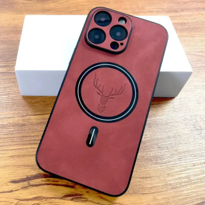 Red suede iPhone case with deer design and MagSafe ring on a wooden surface.