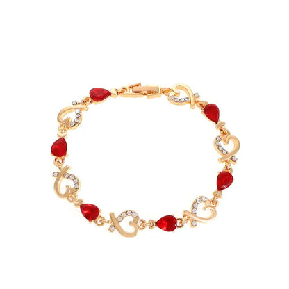 Gold plated bracelet with red teardrop gemstones and sparkling heart accents, perfect for a romantic gift.