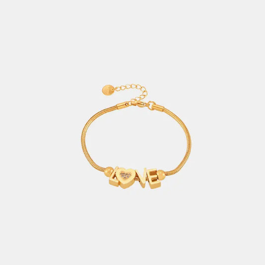 Delicate gold-plated snake chain bracelet featuring LOVE letters with crystal-studded heart charm and adjustable clasp