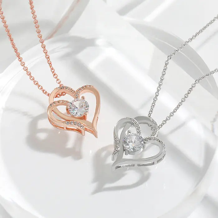 Romantic duo of silver and rose gold heart-shaped necklaces with sparkling stones, perfect for couples.