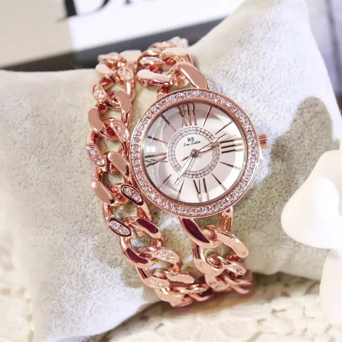 Rose gold wristwatch with crystal accents and Roman numeral design for an elegant women's timepiece.