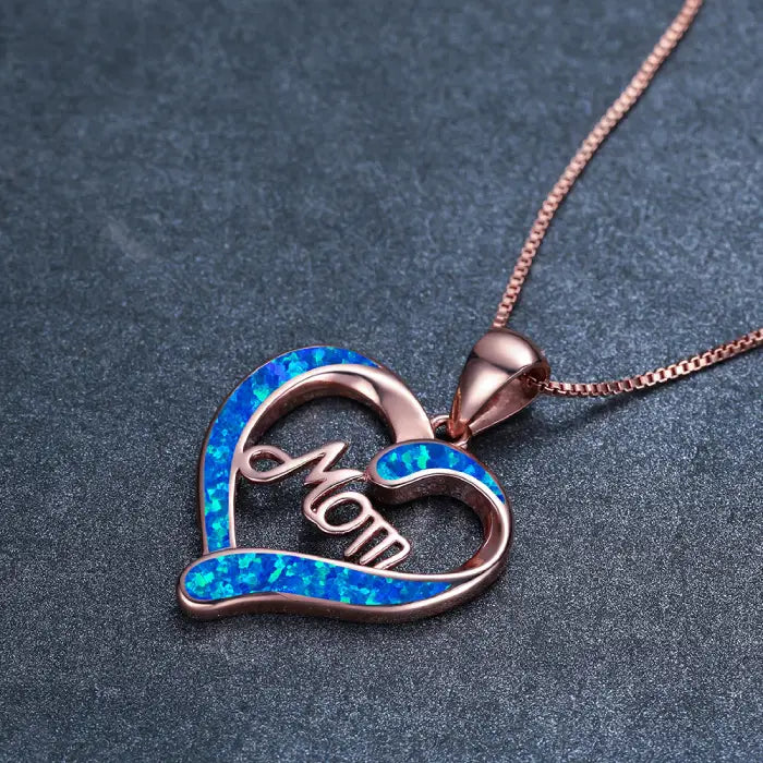 Rose gold mom heart necklace with shimmering blue opal inlay on textured background for special occasions.