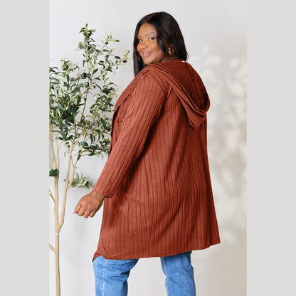 Back view of rust colored hooded cardigan showing ribbed texture and relaxed fit paired with blue denim jeans