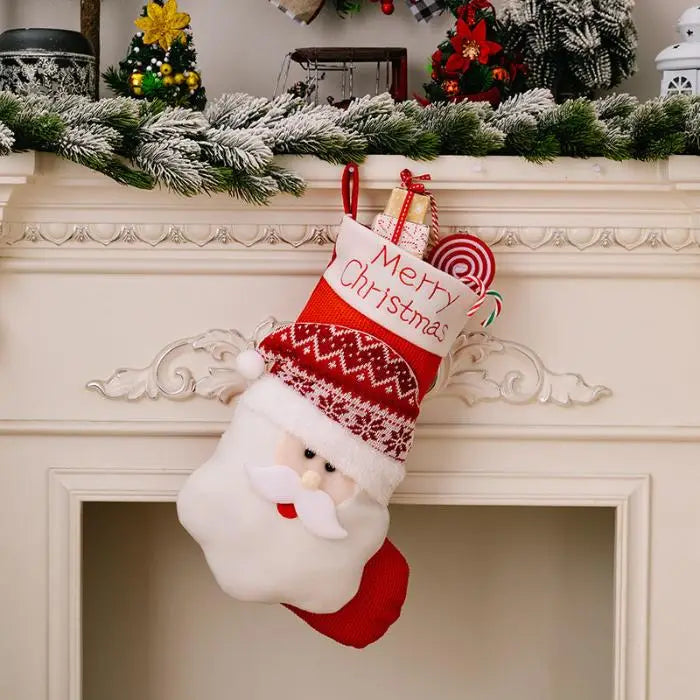 Santa-themed Christmas stocking hanging on white fireplace mantel decorated with snow-covered greenery garland