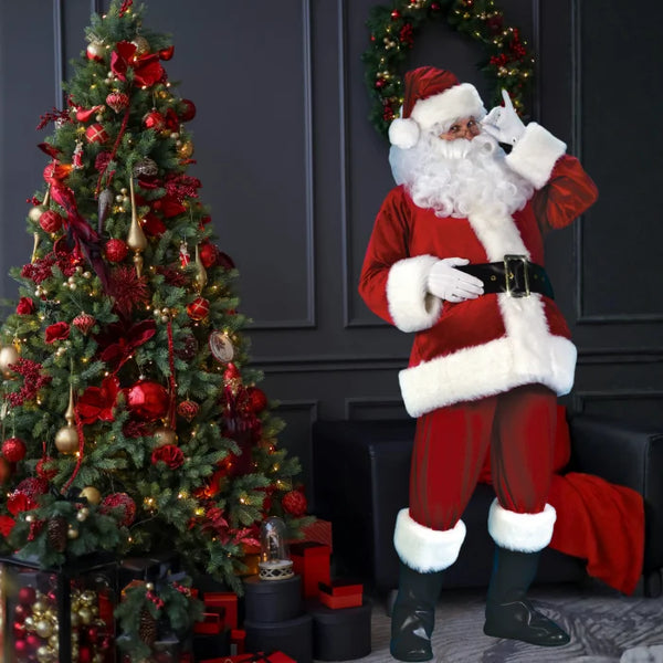 Santa costume adult standing near red and gold Christmas tree with presents and festive decor.