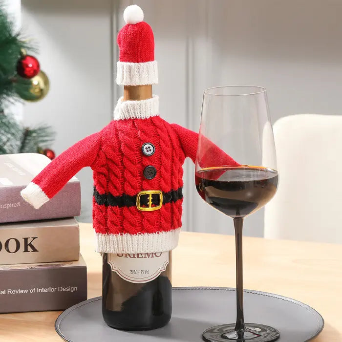 Red cable knit Santa style wine bottle cover with buttons and belt displayed with wine glass and books