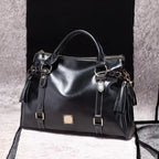 Satchel handbag in black leather on soft beige and black display background