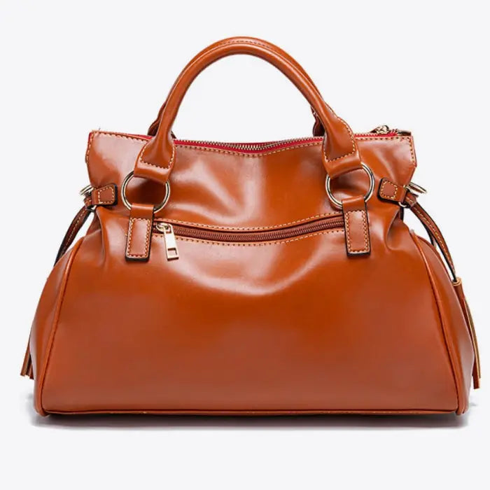 Satchel handbag showing brown leather back with gold zipper and dual handles