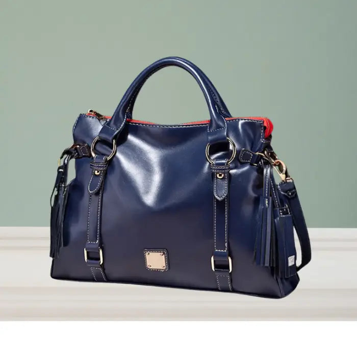 Satchel handbag in navy blue leather with red zipper lining displayed on wooden table surface