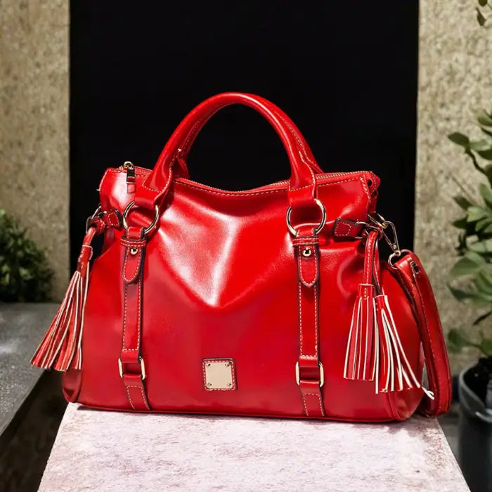 Satchel handbag in glossy red leather on indoor stone and black background