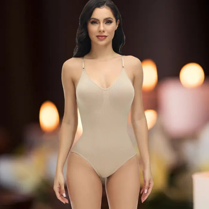 Shapewear underwear in beige modeled front-facing with soft candlelight and warm tones in background.