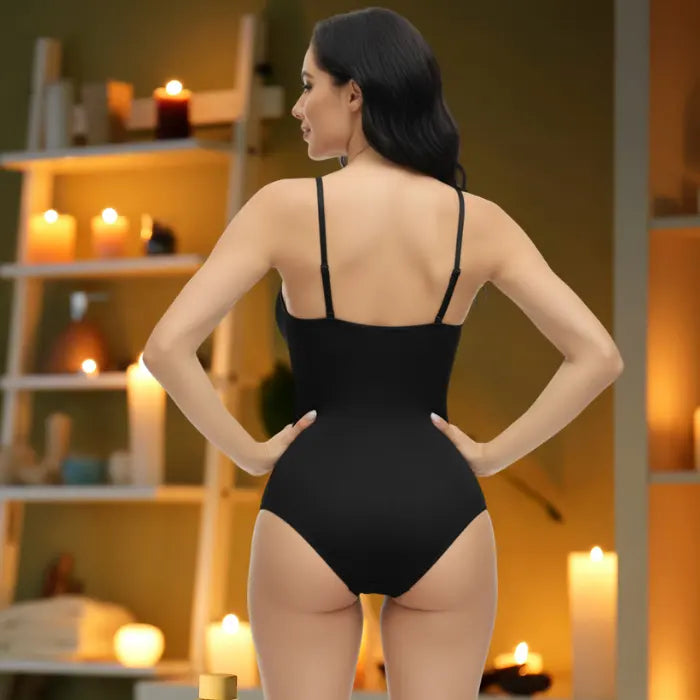 Rear view of black shapewear underwear bodysuit with candlelit spa-like background ambiance.