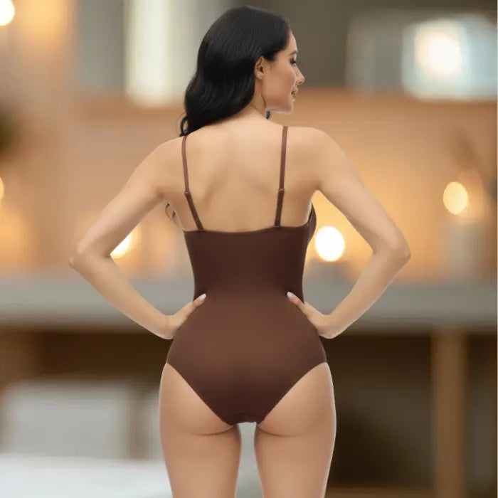 Rear view of brown shapewear underwear bodysuit on model with ambient lighting in luxury setting.