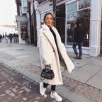 .sherpa coat in white paired with black outfit and sneakers, walking on a stylish London street.